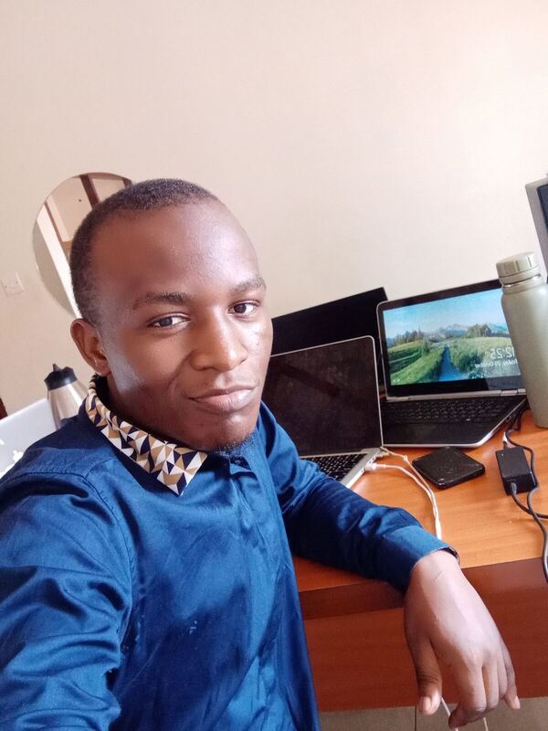 Close portrait at a desk with a laptop open in the background