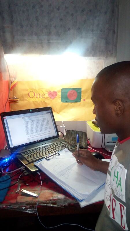Working late on a laptop, an IUT banner on the wall behind