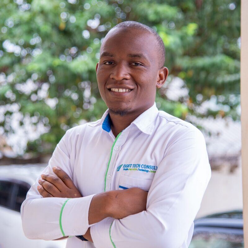 Muhindo Mubaraka, arms folded, wearing a white Eight Tech Consults shirt